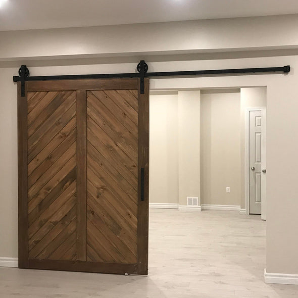 Really big chevron door in barn board brown, with Big Wheel hardware, used to create a separate space in a basement.