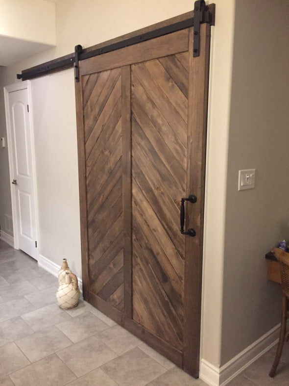 Really big chevron door in barn board brown, with Big Wheel hardware, used to close off a separate space in a basement.